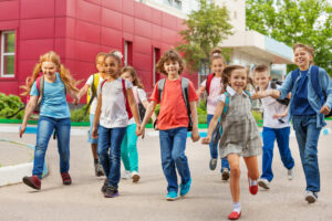 Happy kids with rucksacks walking leaving school