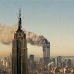 Picture of the Empire State Building in the foreground on September 11th with the buring World Trade Towers in the background