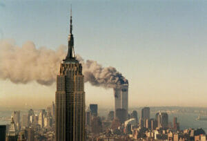 Picture of the Empire State Building in the foreground on September 11th with the buring World Trade Towers in the background