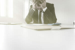 theft of trade secrets: A business man with his head in his hands dispairingnover the loss of his trade secrets. Theft of trade secrets is big problem for businesses.