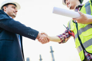 Construction worker and business man in suit shake hands after an in-depth asset search
