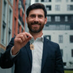 businessman man handing a tenant keys to their new property. How Security Can Help Property Managers Combat High Tenant Vacancy Rates.